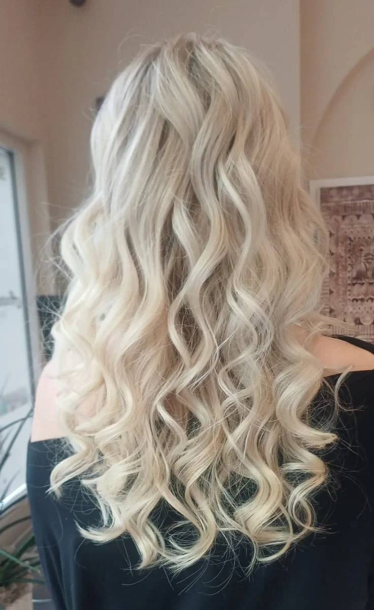 Lange hellblonde Haare mit großen Wellen, von hinten im Salon fotografiert
