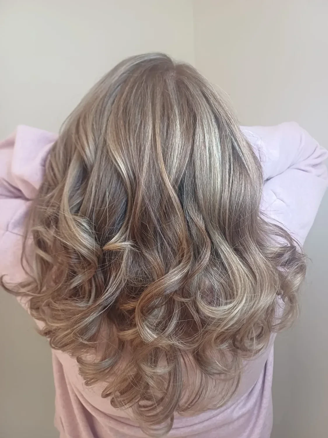 Mittellanges, geföhntes Haar mit beige-aschblonden Strähnen und hellbraunem Ansatz